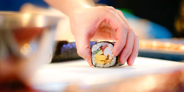 Cropped hand of woman holding food on table