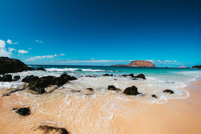 Rocks on beach against blue sky