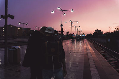 People standing on railroad station platform against sky during dusk