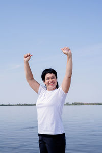 Young man standing in lake against sky