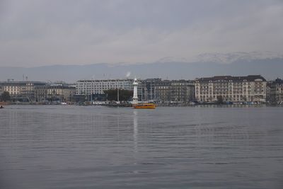 Sea by buildings against sky in city