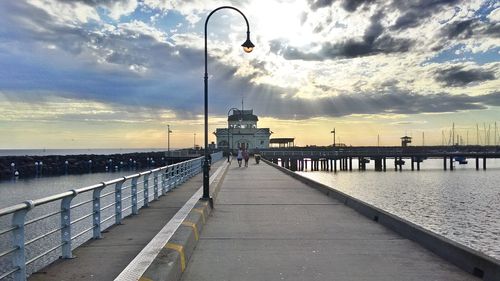 Pier on sea against cloudy sky