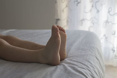 Low section of person lying on bed at home