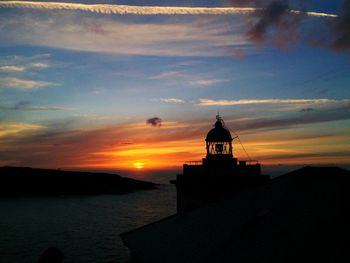 Silhouette church by sea against sky during sunset