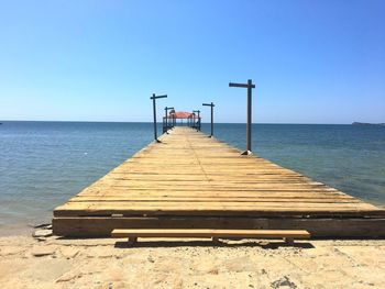 Empty pier on sea against clear sky