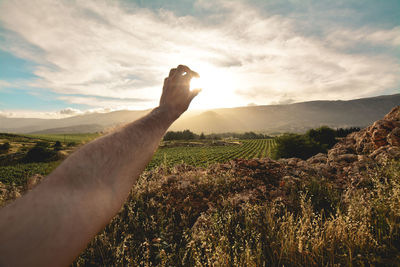 Optical illusion of man hand holding sun against sky