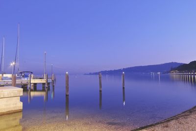 Wooden posts in lake against clear blue sky