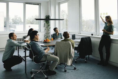 Businesswoman conducting meeting with colleagues sitting at desk in office