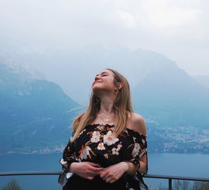 Young woman standing on mountain against sky