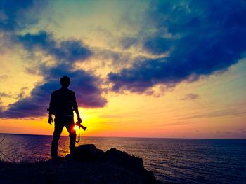 Silhouette man on beach against sky during sunset