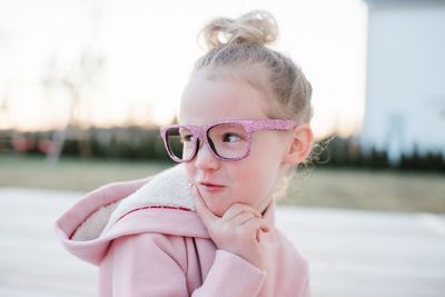 Portrait of a young girl pulling funny faces with pink glasses on