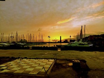 Sailboats moored at harbor against sky during sunset