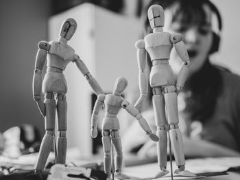 Close-up of wooden figurines with girl in background at home