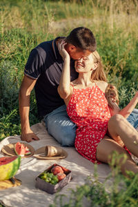 Young couple in love on summer picnic with watermelon. loving couple sitting by the river, talking