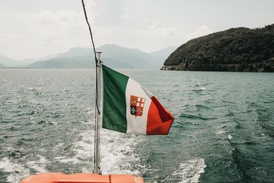 Flag on boat sailing in sea against sky