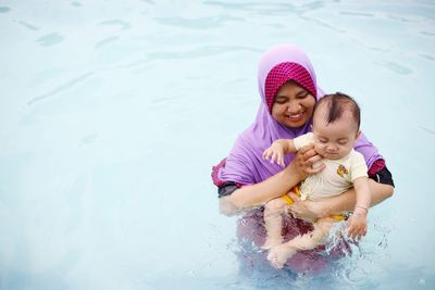 High angle view of happy woman with daughter in pool