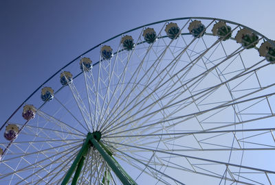 Low angle view of ferris wheel against clear blue sky