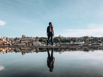 Man standing by river against cityscape