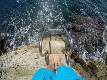 Low section of man standing by sea