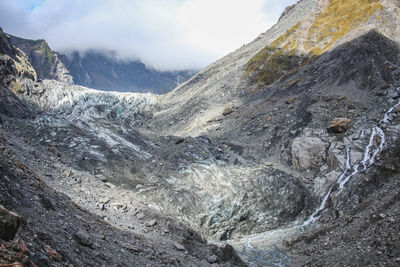 Scenic view of river flowing amidst mountains against sky