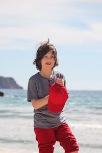 Cute boy on beach against sky