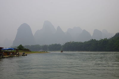 Scenic view of river and mountains against sky