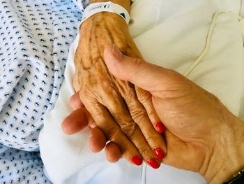 Midsection of couple holding hands on bed