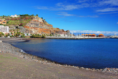 Boats moored in calm sea against built structures