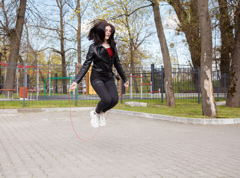 Full length of woman jumping on footpath