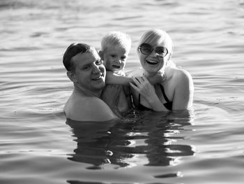 Smiling mother and father with son swimming in sea