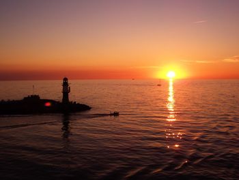 Silhouette man sailing on sea against sky during sunset