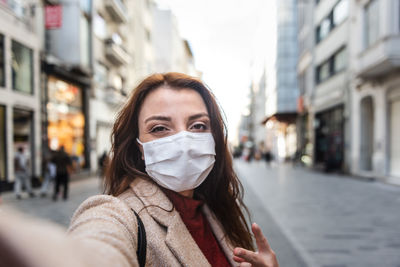 Portrait of woman wearing mask standing on city street