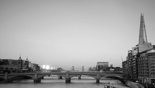 Bridge over river in city against clear sky