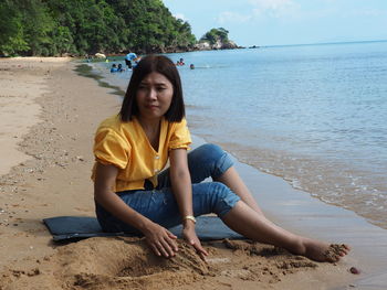 Contemplating woman building with sand while sitting on beach