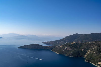 Scenic view of sea and mountains against clear blue sky