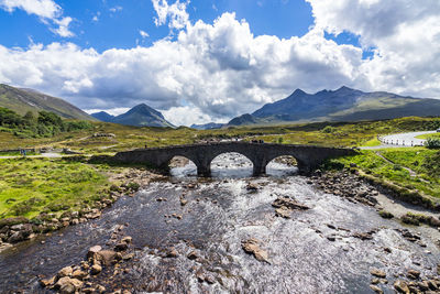 Arch bridge over mountains against sky