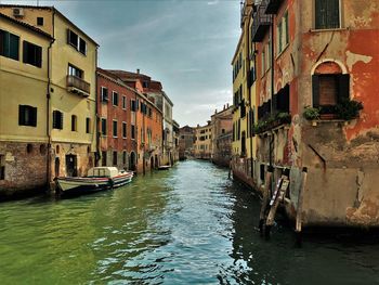 Canal amidst buildings in city against sky