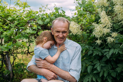 A little girl hugs her grandfather on a walk in the summer outdoors.