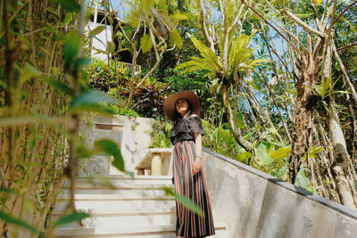 Young woman standing by trees on steps