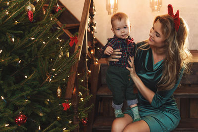 Portrait of siblings sitting on christmas tree