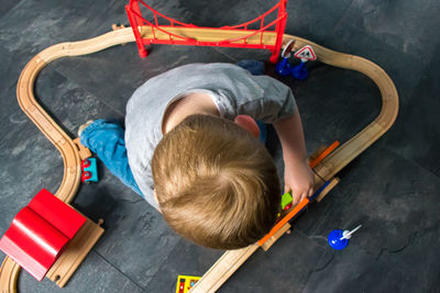 High angle view of boy playing with miniature train at home