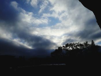 Silhouette of trees against cloudy sky