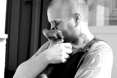 Man embracing cat in sunny day