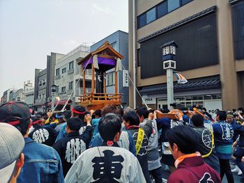 Rear view of people on street against buildings in city