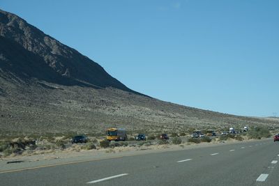 People on road against clear blue sky