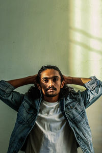 Portrait of young man standing against wall at home