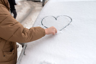 Drawing of a heart in the snow, the snow lies on the car