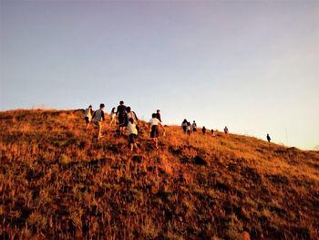 People walking on field against clear sky