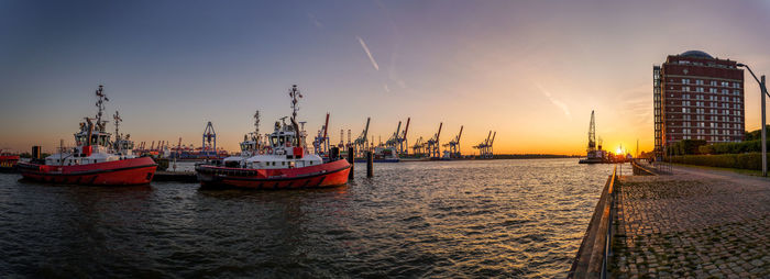 Boats moored at harbor against sky during sunset