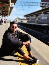Portrait of young man sitting on railroad station